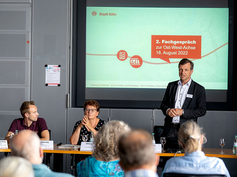 Menschen hören eine Präsentation im Fachgespräch August 2022 zu der Ost-West-Achse Köln.